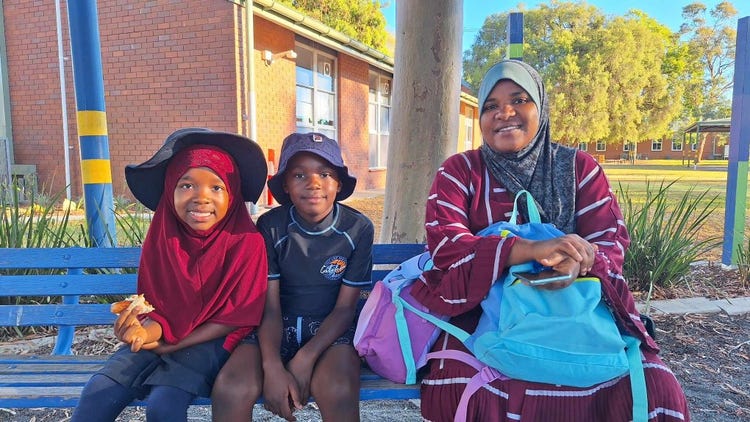 Female adult sitting with two children.